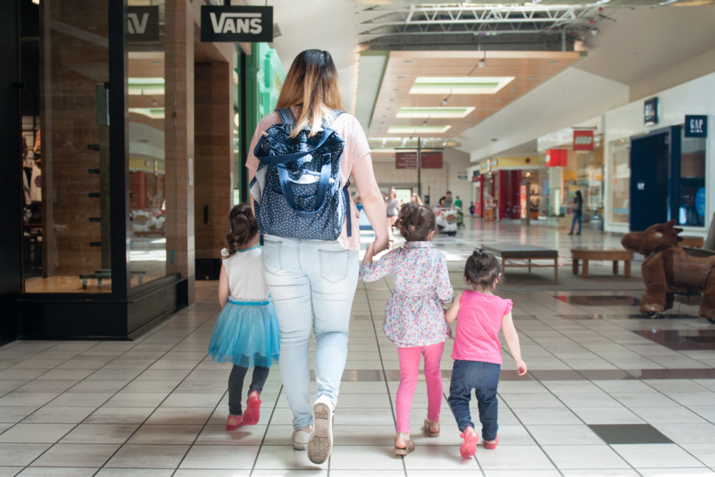 Mom holding her daughter's hands as they walk through the mall on a family session