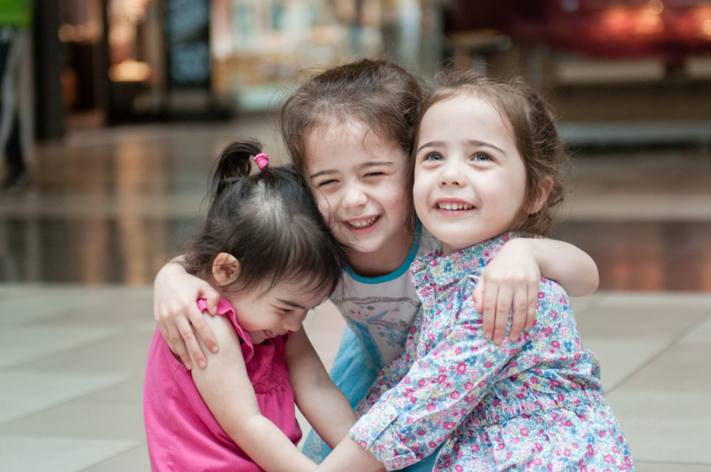 Twin sisters and their little sister hugging during Tina Captures Photography Family Session