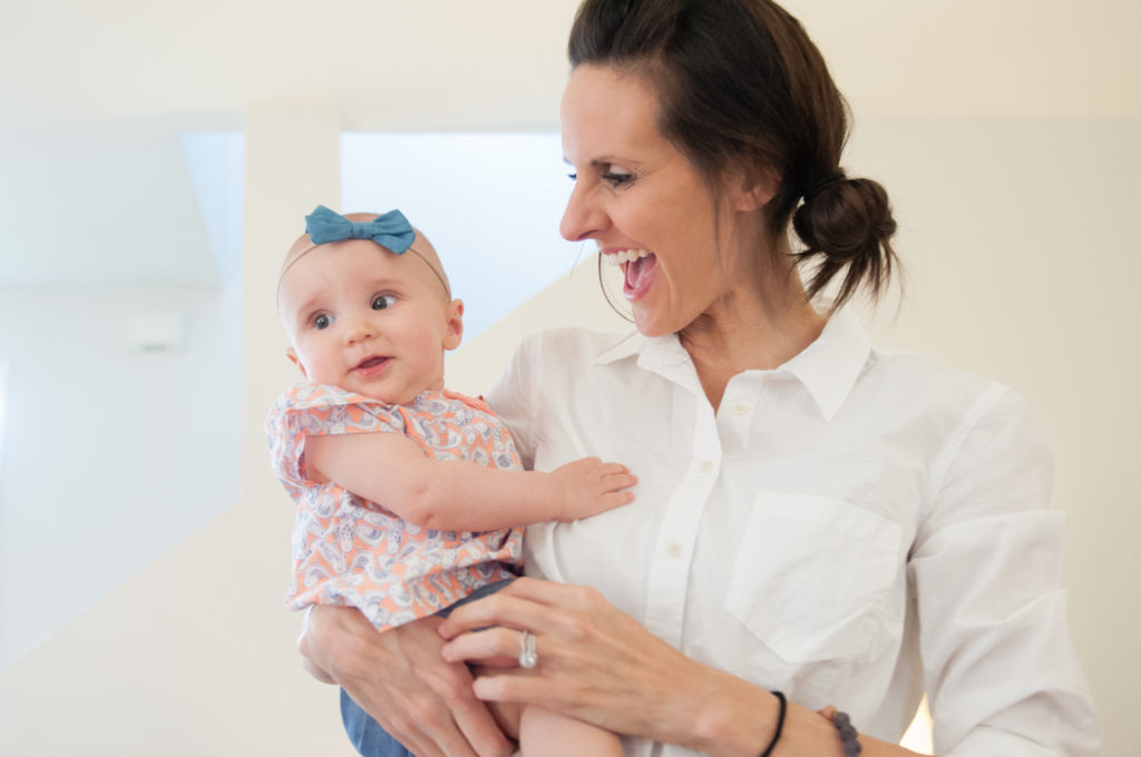 Emma being held by her mom in their living room for Emma's 6 month session by Tina Captures Photography