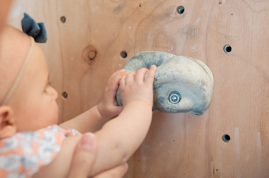 Emma holding on to the homemade rock wall in the garage