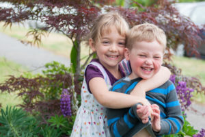 Rya hugging her brother Arlo during a Tina Captures family session in the backyard
