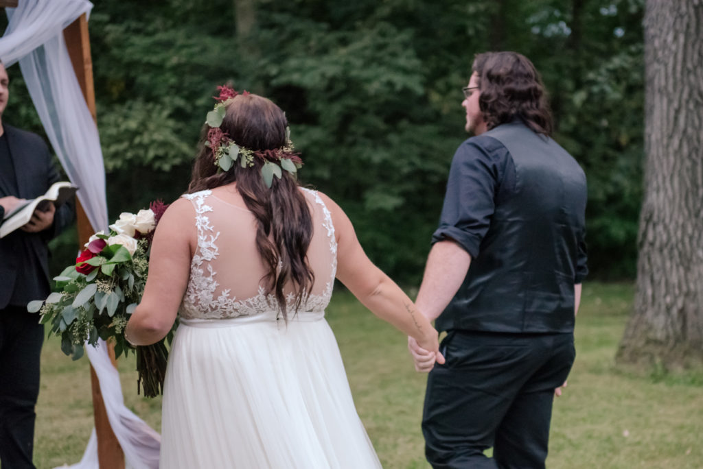 Jesse & Paige McEachran Homestead Winery outdoor wedding ceremony venue bride and groom holding hands by Tina Captures Photography