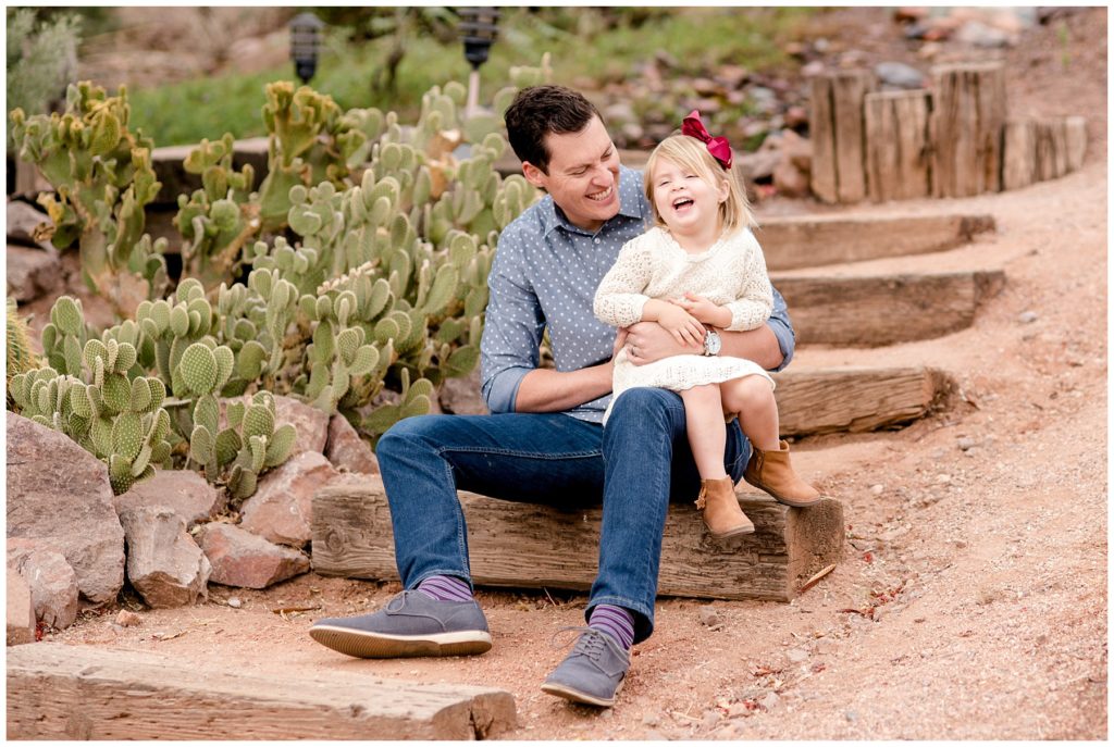 Dad holding his daughter on his lap during desert family session