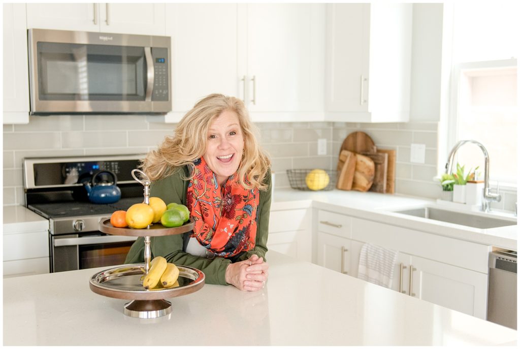 Designer Teri Whitney portrait in a light and bright spring kitchen. Designed by McFadden & Grace. Tina Captures Photography.