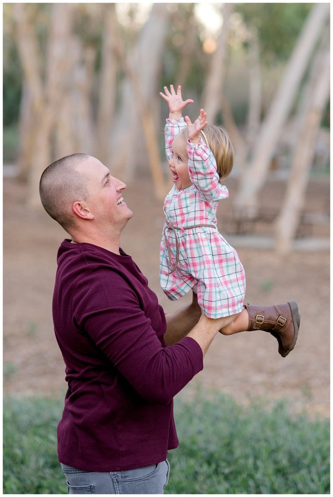 Dad holding his daughter as she joyfully has her hands in the air