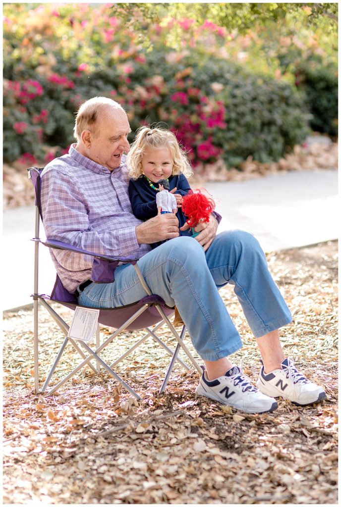 Grandpa holding his granddaughter in his lap and playing during orange county family photography session